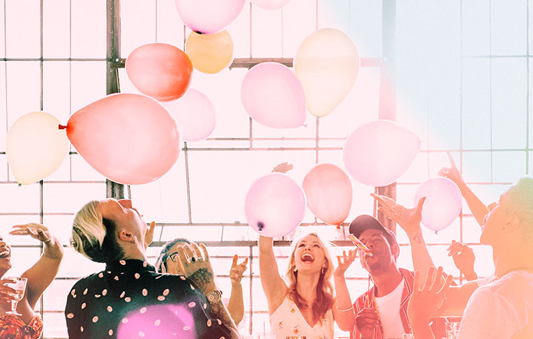 Un grupo de amigos disfruta de su tarjeta Senator lanzando globos al aire